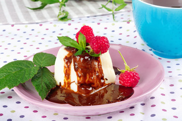 Cream pudding with chocolate sauce, raspberry and mint on  tablecloth