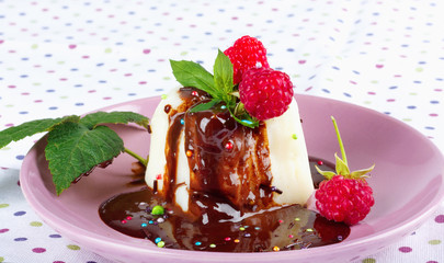 Cream pudding with chocolate sauce, raspberry and mint on  tablecloth
