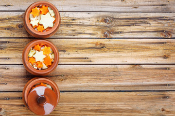 Traditional rustic home vegetable  ragout in three clay pots on old vintage wooden table