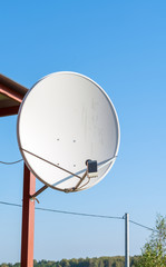 Large satellite dish antenna on the garden house pillar