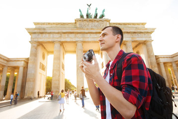 Travel in Berlin, tourist man with camera in front of Brandenburg Gate, Berlin, Germany