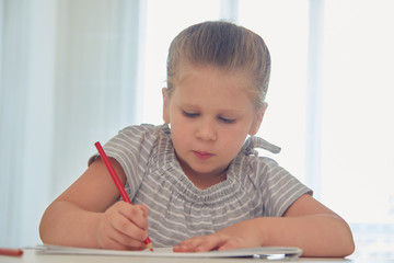 Naklejka premium Little girl drawing with pencils at home