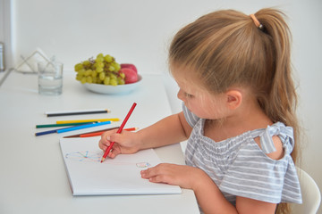 Little girl drawing with pencils at home