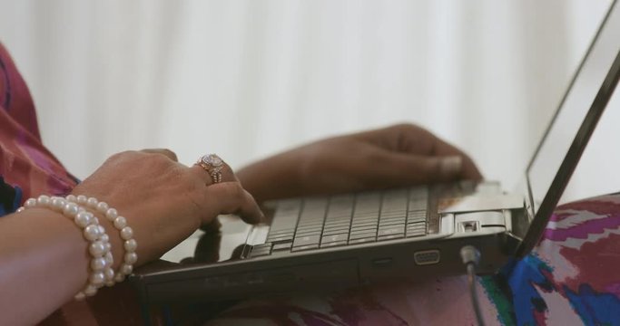 Close up of a woman using a laptop computer with a gift card handy to do some online shopping.