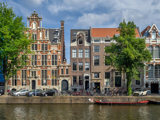 Fototapeta premium Buildings and boats along Amsterdam's beautiful canals in central Amsterdam during the day. The canals are one of Amsterdam's main attractions.