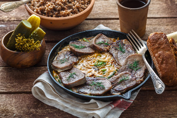 Beef tongue in cast iron skillet with cream sauce, rustic style.