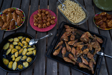 Table with variety food top view. Party snack food table with baked potatoes, fried chicken drumsticks, italian pasta and puff pastry buns bread, close-up