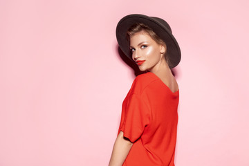 Portrait of young pretty woman with shiny pure skin on pink background. Well-dressed model in...