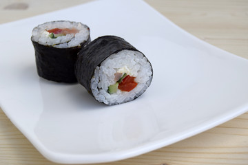 Sushi a dish of traditional Japanese cuisine cooked from rice, a salmon, vegetables and a nori. Sushi are on a dish. Close up.