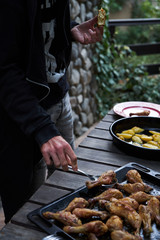 Catering buffet food table with baked potatoes, fried chicken legs, pasta and vegetable salad. People at a party taking different food, outdoor. Colleagues Buffet Party Brunch Dining Concept