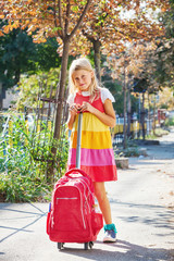 Cute 8 years old schoolgirl carry backpack with wheels