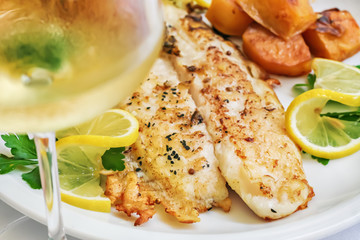 Fried white fish meal with lemon slices, parsley and potatoes