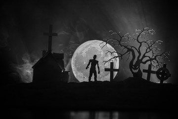 Scary view of zombies at cemetery dead tree, moon, church and spooky cloudy sky with fog, Horror...