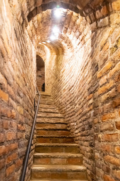 Naklejka Narrow staircase in old cellar with brick walls.