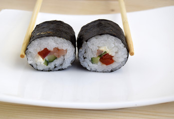 Sushi a dish of traditional Japanese cuisine cooked from rice, a salmon, vegetables and a nori. Sushi are on a dish. Close up.