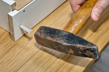 Assembly furniture, installation of drawer using hammer and dowel.
