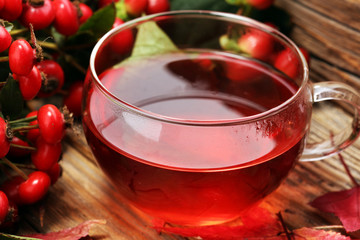 Tea. cup of herbal Dog rose tea with bunch branch Rosehips, types Rosa canina hips. Medicinal plants and herbs composition.