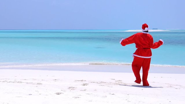 Man in Santa Claus Hat dancing on sandy beach
