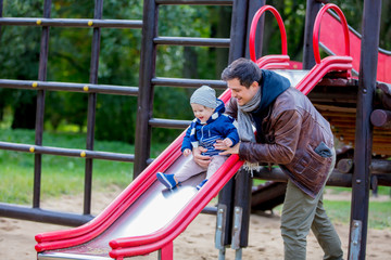 Young father play with a child on a playground. Autumn season time
