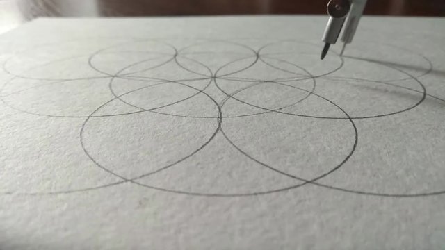 The compasses draw a circle on a piece of paper