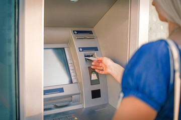 Young woman taking money from ATM