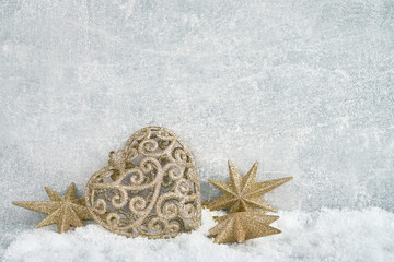 Golden Christmas decoration in snow on gray background. Copy space.