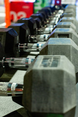 Black rubber dumbbells. Hexagonal heavy duty weight set used for serious hardcore gym workouts,...
