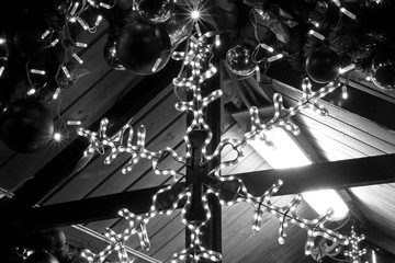 a large Christmas garland in the shape of a beautiful snowflake, decorates the city and shines brightly at night, black and white close-up photo