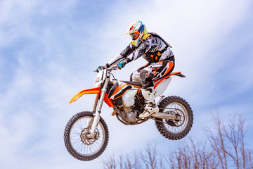 racer on a motorcycle in flight, jumps and takes off on a springboard against the snowy mountains