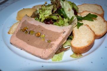 Restaurant serving: liver pate stuffed with nuts, served with pickled pears and letucce  .