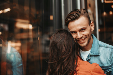 Obraz premium Beaming male embracing girl while speaking with her outside. Glad couple spending time together concept