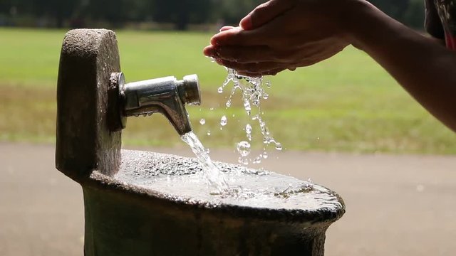 Someone drinking water from a water tap