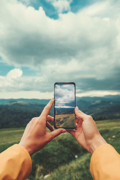 Close up of a modern smartphone in hands of a female traveler making photos and resting in the mountains