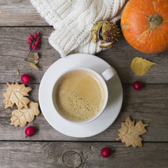 Coffee cup, knitted scarf, dry leaves, cookies, hawthorn and barberry fruits on a wooden background. Concept cozy atmosphere with a cup of coffee. Copy space, flat lay