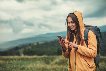 Nice young woman using her mobile phone while enjoying her weekend in the mountains