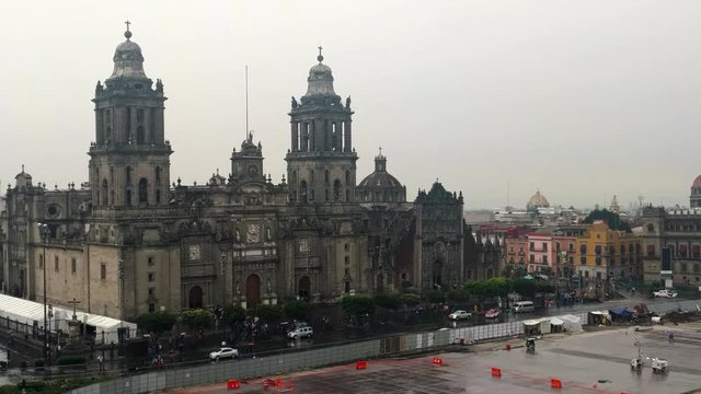 Mexico City Metropolitan Cathedral on a rainy afternoon. Traffic and pedestrians moving around Constitution Plaza. Zocalo, Federal District.