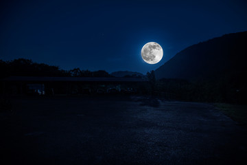 Mountain Road through the forest on a full moon night. Scenic night landscape of dark blue sky with moon. Azerbaijan