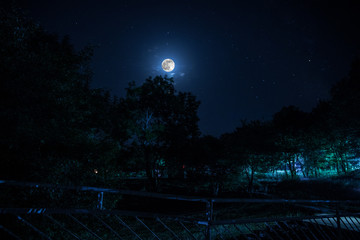 Mountain Road through the forest on a full moon night. Scenic night landscape of dark blue sky with moon. Azerbaijan