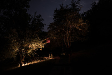 Fototapeta premium Mountain night landscape of building at forest at night with moon or vintage country house at night with clouds and stars. Summer night.