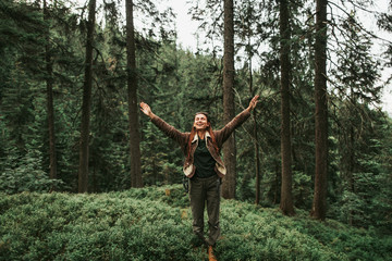Obraz premium Jestem szczęśliwy i wolny. Pełnometrażowy portret energicznej młodej damy z zamkniętymi oczami, cieszącej się podróżami po lesie. Z radością i uśmiechem rozkłada ramiona