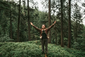 Poster Ik ben blij en vrij. Volledig portret van een pittige jonge dame met gesloten ogen die geniet van reizen in het bos. Ze spreidt haar armen met vreugde en glimlacht © Yakobchuk Olena