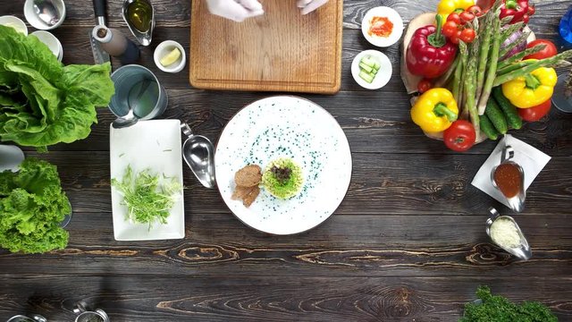 Hands of chef working. Tasty dish on wooden table.