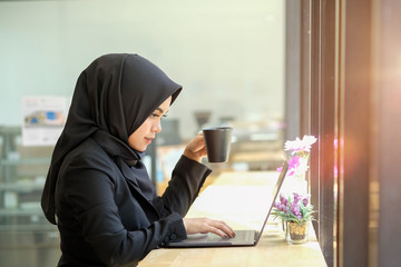 Attractive female Arabic working on laptop computer on desk.