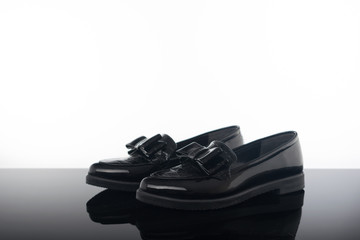  pair black glossy loafer flat woman shoes on black reflective background
