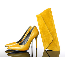 yellow high heels pointed woman shoes and hand bag on reflective floor