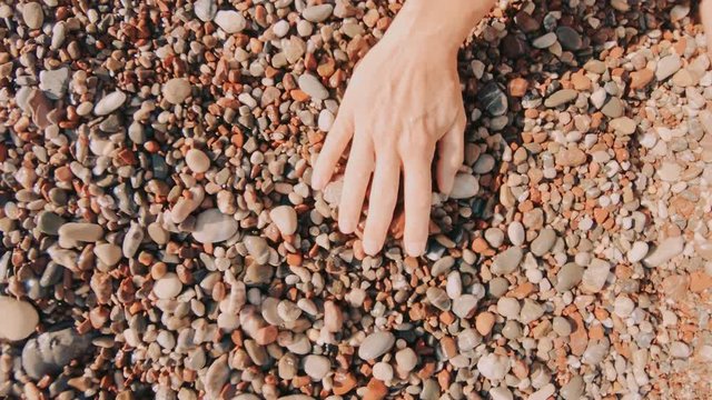 A Female Hand Stroking Over Wet Colorful Sea Pebbles By The Seashore In Slow Motion.