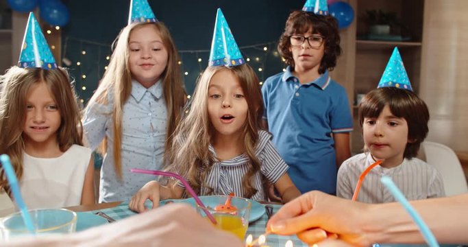 Children celebrating birthday party, excitedly waiting to blow out the candles on birthday cake. Group of kids having fun on birthday party - happy childhood concept 4k