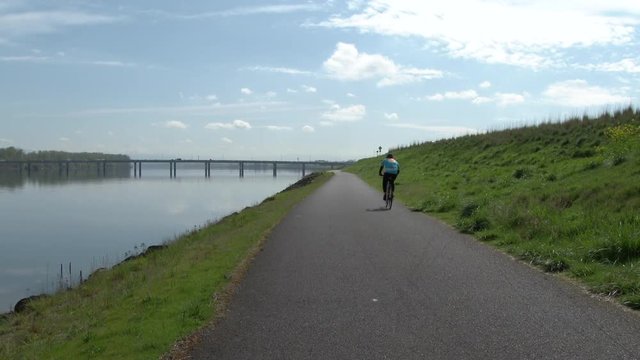 One unrecognizable person riding bicycle down bike path by the Columbia River in Portland, Oregon.