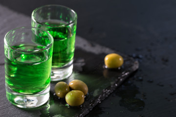 Two glasses of strong absinthe and green olives