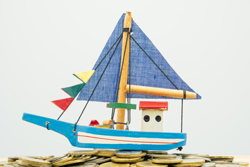 Model boat is placed on a pile of coins.using as background business concept and finance concept with copy spaces for your text or design.